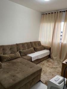 ein Wohnzimmer mit einem braunen Sofa und einem Fenster in der Unterkunft Apartamento Mobiliado para seu conforto in Caruaru