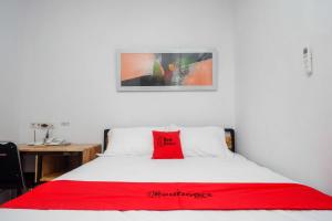 1 dormitorio con una almohada roja en la cama en RedDoorz Plus near Patung Kuda Undip, en Jatingaleh