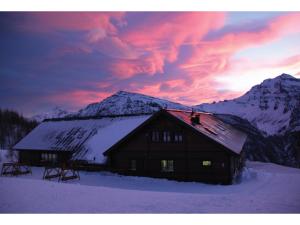 a barn in the snow with mountains in the background at Rifugio 2000 in Alpe Ciamporino