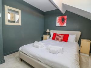a bedroom with a large white bed with red pillows at East Cottage in Malton