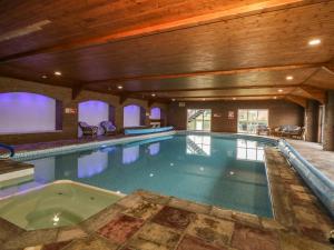 a large swimming pool with a hot tub in a building at Cowshed Cottage in Malton