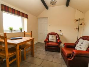 ein Wohnzimmer mit einem Tisch und 2 Stühlen in der Unterkunft Cowshed Cottage in Malton