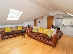 a living room with two leather couches and a kitchen at The Hideaway in St Ives