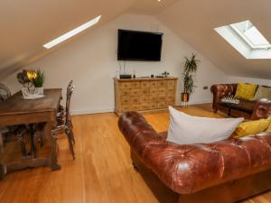 a living room with a leather couch and a television at The Hideaway in St Ives