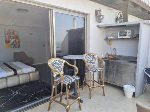 Il dispose d'une cuisine et d'un balcon avec deux chaises et une table. dans l'établissement Penthouse Apartment On The Beach, à Bat Yam