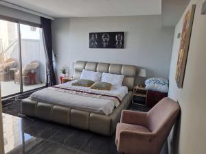 a bedroom with a large bed and a chair at Penthouse Apartment On The Beach in Bat Yam