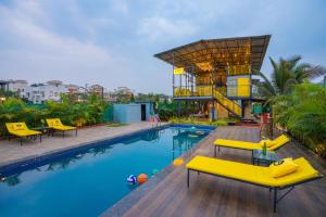 a swimming pool with yellow chairs and a building at The Hosteller Lonavala in Lonavala