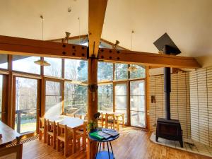 a kitchen and dining room with a fireplace and windows at Pension Gooseberry in Furano