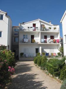 a white apartment building with a balcony and flowers at Apartments Vidović in Vodice