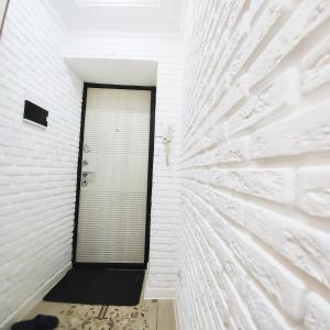 a hallway with a white brick wall with a door at Красивый однокомнатный люкс в районе вокзала in Karagandy