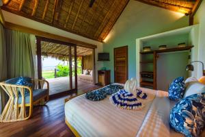 a bedroom with a bed and a chair in a room at Segara Lombok Beach Resort in Selong Belanak