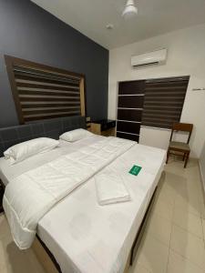 a bedroom with a large white bed and a chair at PMR GRANDAYS in Malappuram