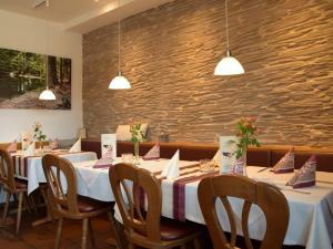 comedor con mesas y sillas y pared de piedra en Landgasthof Zum Jossatal, en Bad Soden-Salmunster