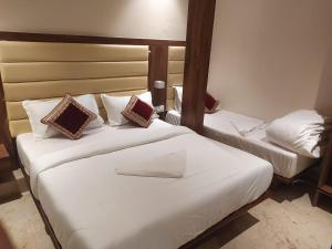 2 Betten in einem Hotelzimmer mit weißer Bettwäsche und Kissen in der Unterkunft Hotel Adams Inn Near Mumbai Airport in Mumbai