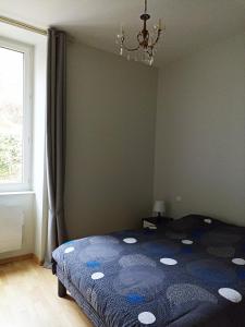 1 dormitorio con 1 cama con edredón azul y ventana en St Nectaire- Appartement Terrasse Privée- 4 personnes en Saint-Nectaire
