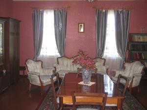 a dining room with a table and chairs and two windows at Guesthouse Gegi in Kutaisi