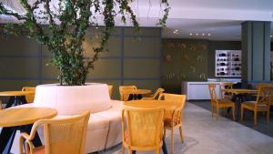 a restaurant with tables and chairs and a large pot with a plant at Aitch Boutique Hotel - an LIH Hotel in Madaba