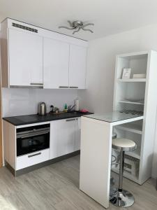 a kitchen with white cabinets and a stove and a stool at B&B Kelly Plus in Lausanne