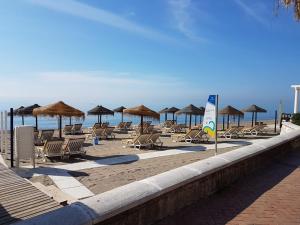 a row of beach chairs and umbrellas on a beach at Fuengirola Center in Fuengirola
