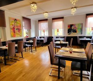 a restaurant with tables and chairs in a room at Arthotel ANA Style Augsburg in Augsburg