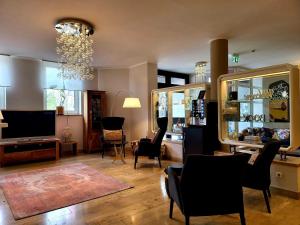 sala de estar con sillas, TV y lámpara de araña en Arthotel ANA Style Augsburg en Augsburg