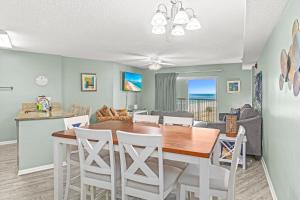 comedor y sala de estar con mesa y sillas en Tradewinds Unit 406, en Orange Beach