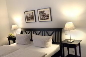 a bedroom with a bed with two lamps and two pictures on the wall at Louisenhof Ferienapartments und Wellness in Burg