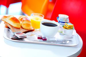 a tray with a breakfast of bread and coffee and orange juice at CLASSIC HÔTEL Reims Est - Taissy in Reims