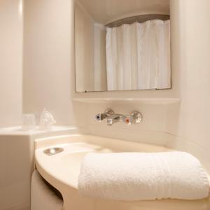 La salle de bains blanche est pourvue d'un lavabo et d'un miroir. dans l'établissement Premiere Classe Reims Est - Taissy, à Reims