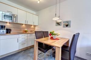 eine Küche mit einem Holztisch und schwarzen Stühlen in der Unterkunft Residenz am Balmer See - BS 48 mit Wellnessbereich in Balm