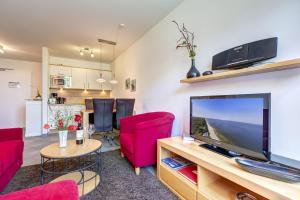 ein Wohnzimmer mit einem Flachbild-TV und roten Stühlen in der Unterkunft Residenz am Balmer See - BS 48 mit Wellnessbereich in Balm