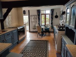 una cocina con armarios azules y una mesa con sillas en Les quatre vents, en Ars