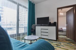 salon z niebieską kanapą i telewizorem w obiekcie Apartamenty Świnoujście - Aleja Baltic Park Molo C206 w Świnoujściu