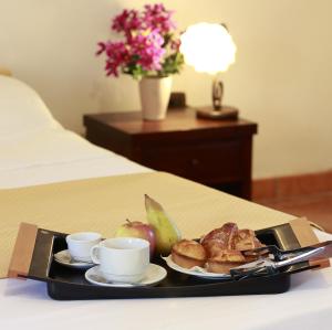 a tray with a plate of food and cups on a bed at Masseria Nucci - Autentica Dimora Storica in Nardò