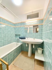 bagno con piastrelle blu, lavandino e vasca di VILLA PARADIS Vue Mer Saint-Raphael a Drammont