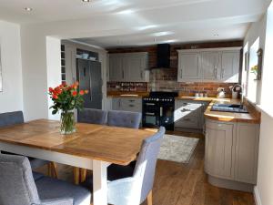 cocina con mesa de madera y sillas azules en Honeysuckle Cottage, en Oughtibridge