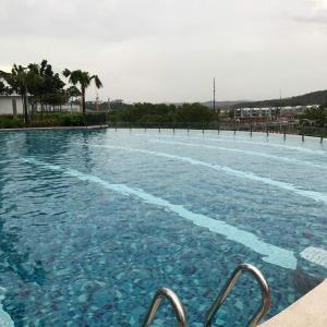 a large swimming pool with blue water and palm trees at LA 1 Homestay Putrajaya Dwiputra in Putrajaya