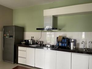 a kitchen with white cabinets and a stainless steel refrigerator at LA 1 Homestay Putrajaya Dwiputra in Putrajaya