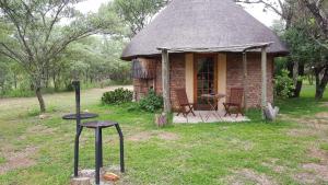 a small hut with a table and chairs in the grass at Olievenhoutsrus Guest- and Game Farm in Vaalwater