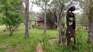 a statue in a park with a building and trees at Olievenhoutsrus Guest- and Game Farm in Vaalwater