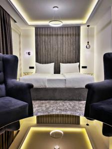 a bedroom with a bed and two chairs and a table at Hotel Boutique Bristol in Sarajevo