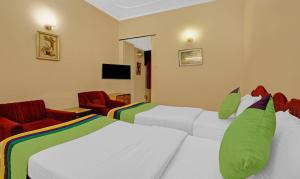a hotel room with two beds and two chairs at Treebo Trend Mira Inn in Kolkata