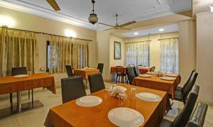 Treebo Trend Mira Inn في كولْكاتا: غرفة طعام مع طاولات وكراسي خشبية