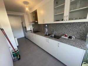 uma cozinha com armários brancos e bancadas em granito em Grupo Gontad Apartamento Villa Amparo Laxe em La Coruña