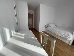 een witte kamer met 2 bedden en een tafel bij Grupo Gontad Apartamento Villa Amparo Laxe in A Coruña