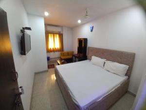 sypialnia z białym łóżkiem i telewizorem w obiekcie Metro Regency Near Lucknow Junction- Couple Friendly Hotel w mieście Lucknow