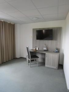 a room with a desk and a television on a wall at Businesshotel & Appartements Stuttgart-Vaihingen in Stuttgart