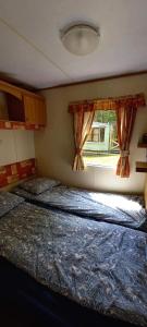 a bedroom with a bed and a window at Domki Holenderskie Mazury Leleszki in Leleszki