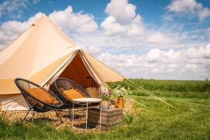 a tent with chairs and a table in a field at Smuk Lytse Bell Tent in Echtenerbrug