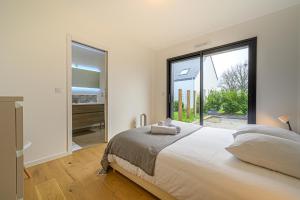 a bedroom with a large bed and a large window at LE GRAIN DE CHARME - Maison contemporaine proche golfe du Morbihan in Sarzeau